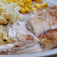 A close up photo of slow cooker sticky chicken resting on a plate with corn on the side.