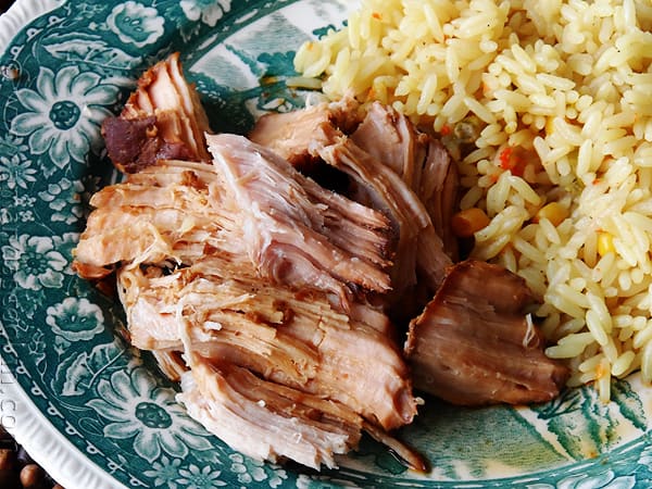 A close up photo of slow cooker oriental pork roast on a plate next to rice.