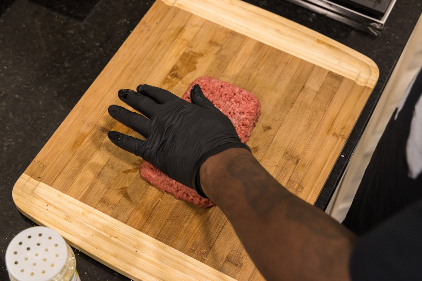hand pressing down on ground beef