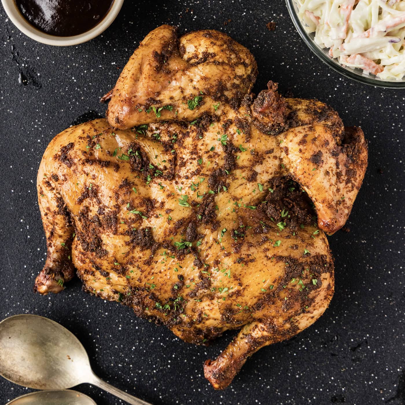 Close up photo of a Smoked Spatchcock Chicken on a black board