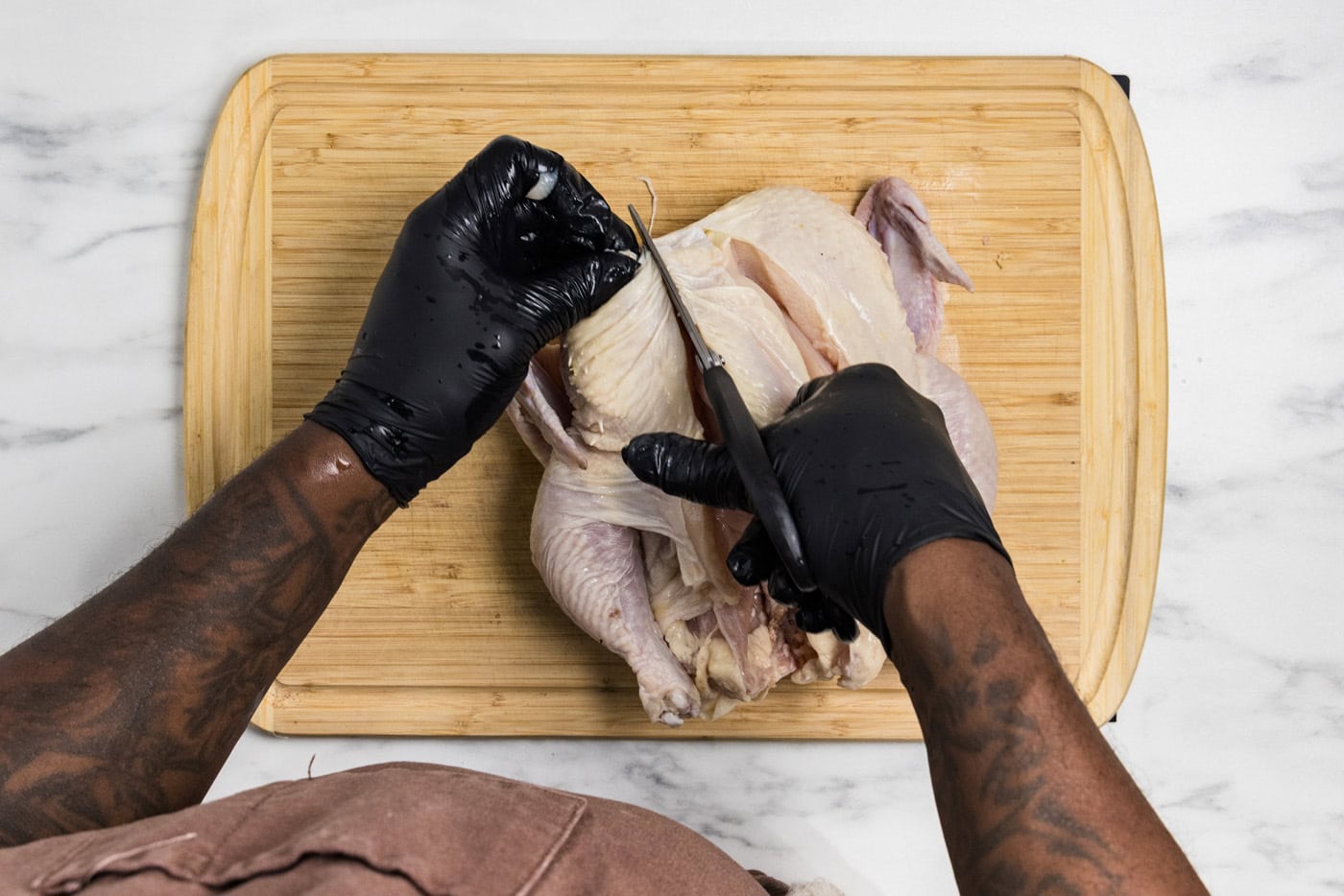 Kitchen shears cutting through raw chicken's back to spatchcock