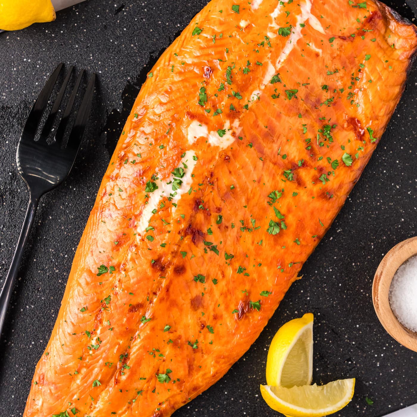 Smoked Trout on a board with lemons and a fork to the side