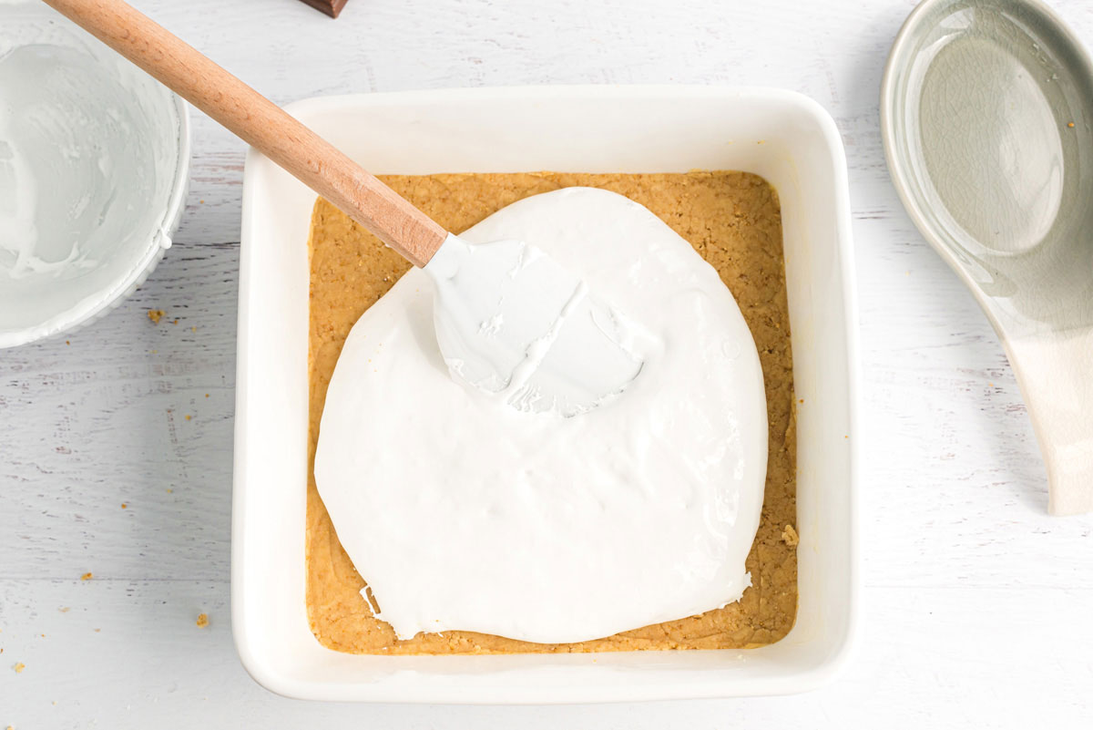 Spreading marshmallow creme over dough in pan