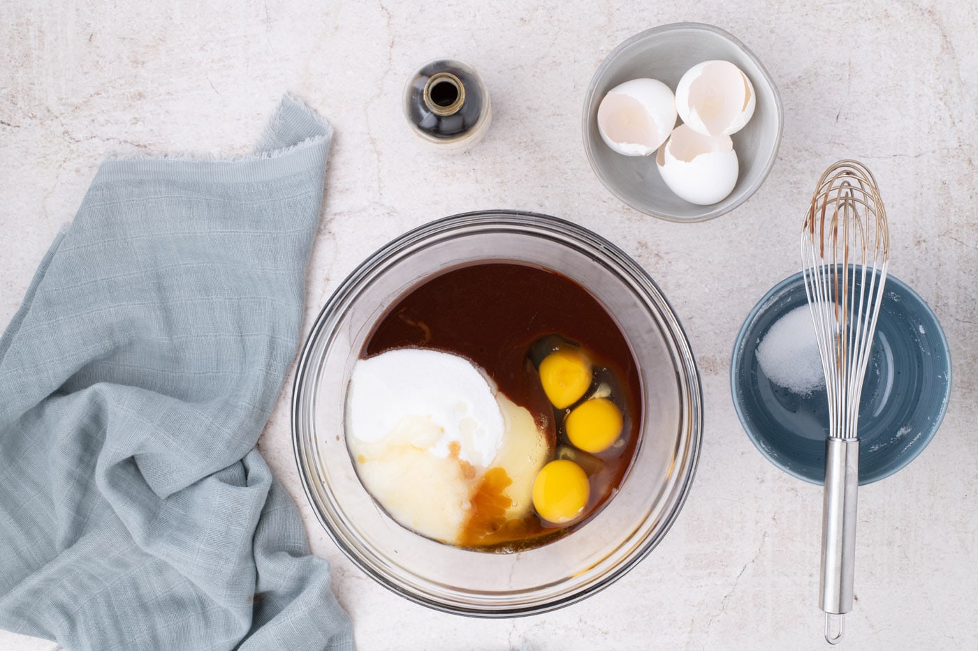 adding eggs and sugar to melted chocolate in a bowl