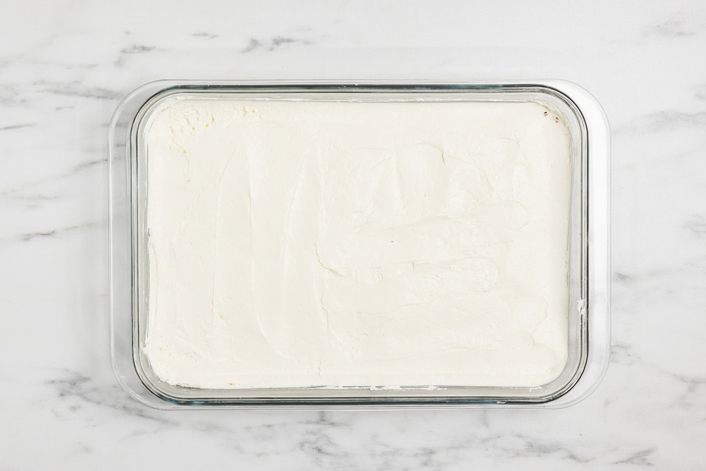 cheesecake layer over graham crust in a baking dish