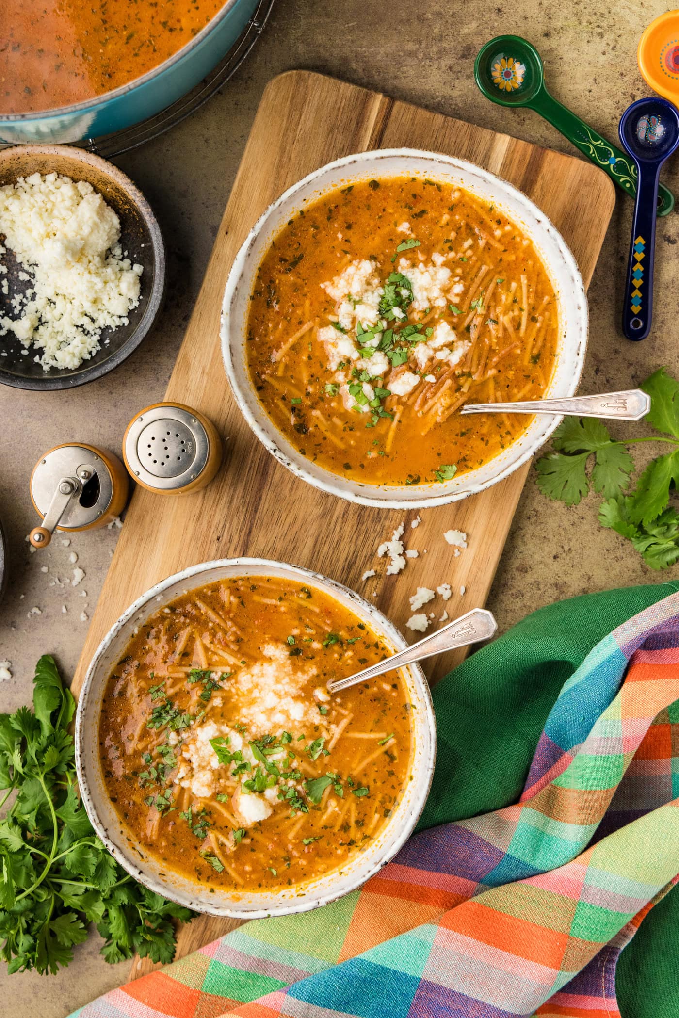 overhead photo of 2 bowls of Sopa de Fideo with cotija cheese