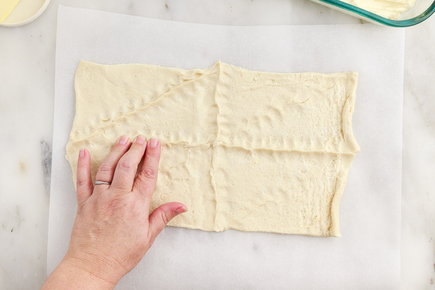 hand pressing the seams of crescent dough together