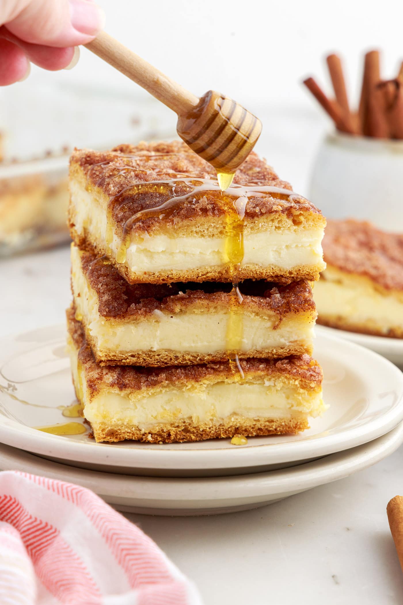 Honey drizzled over a stack of Sopapilla Cheesecake squares