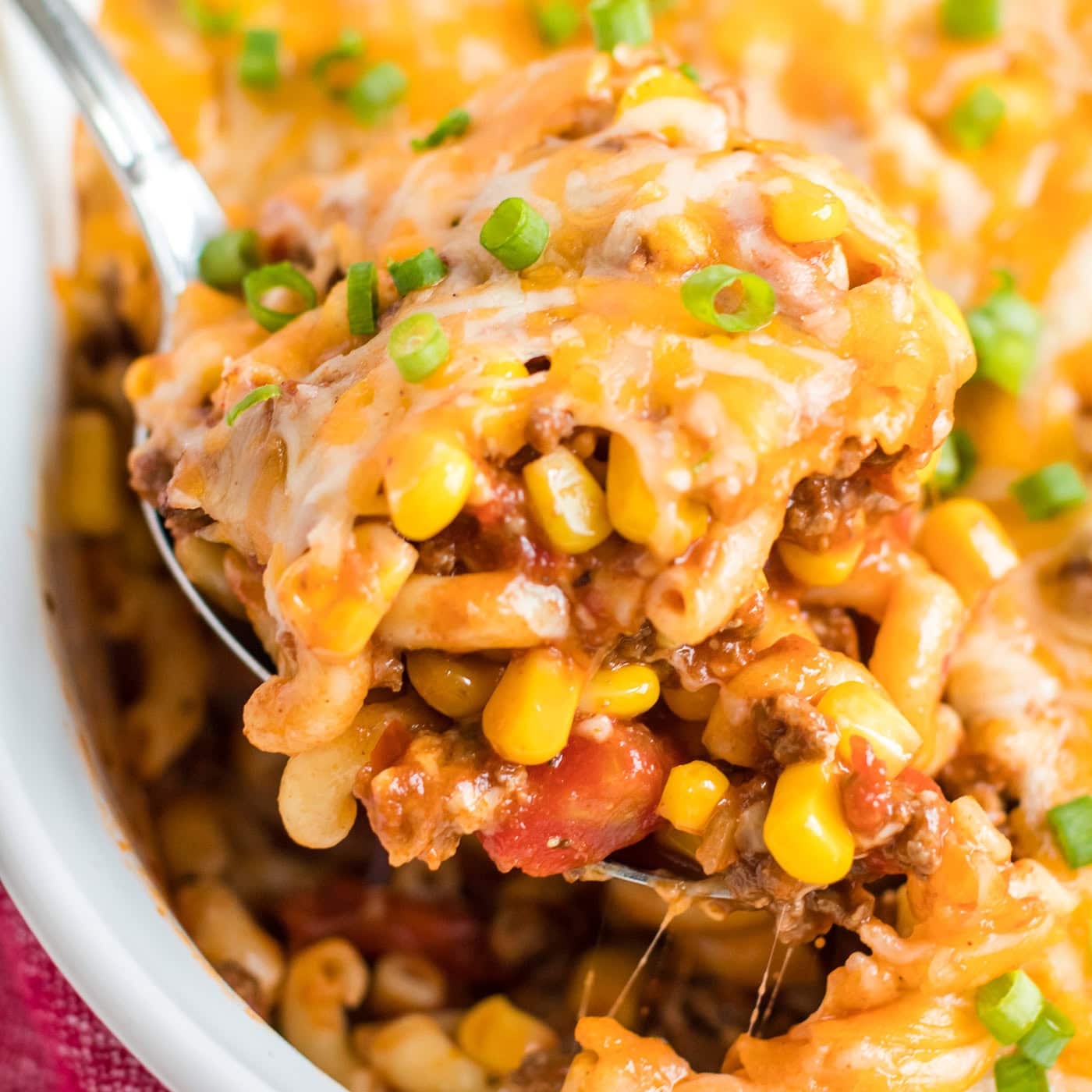 spoon lifting out ground beef casserole from dish