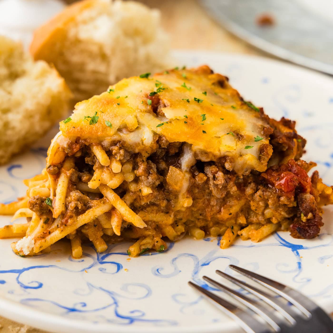 Close up slice of spaghetti pie with melted mozzarella on a blue and white plate