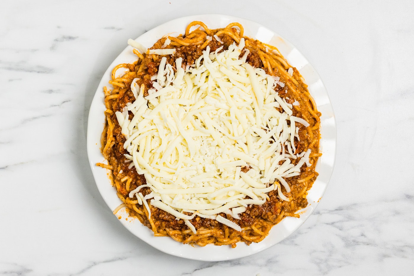 Shredded mozzarella sprinkled over the meat sauce before baking
