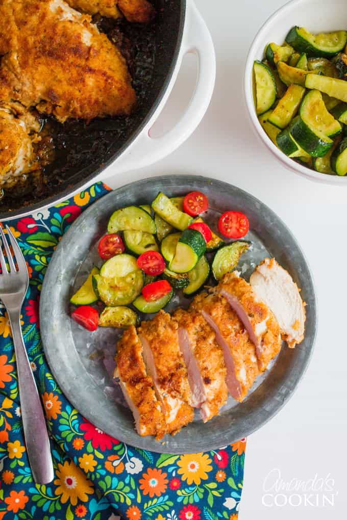 Sliced chicken on plate with zucchini and tomato side