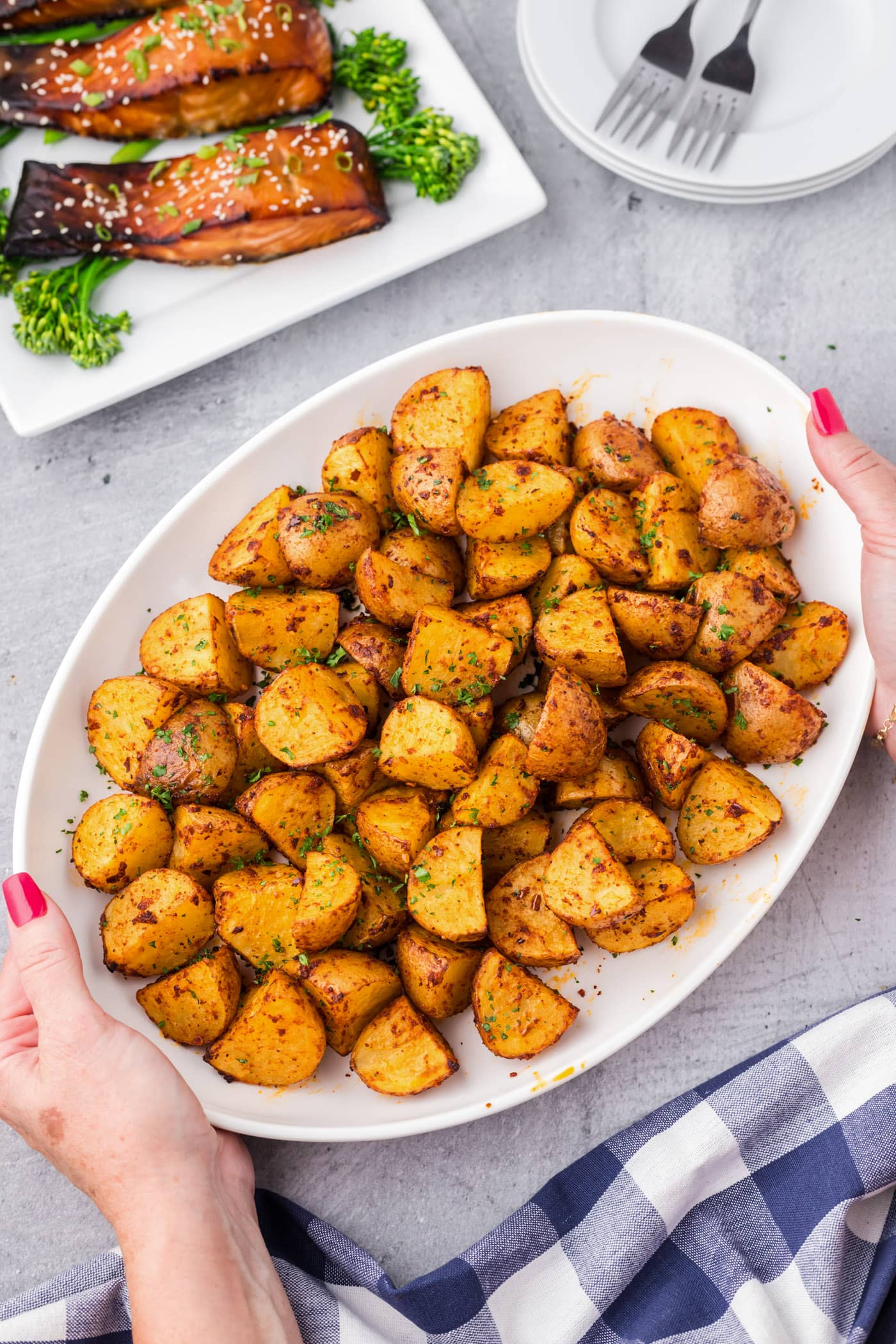 Hands holding a platter of Spicy Potatoes
