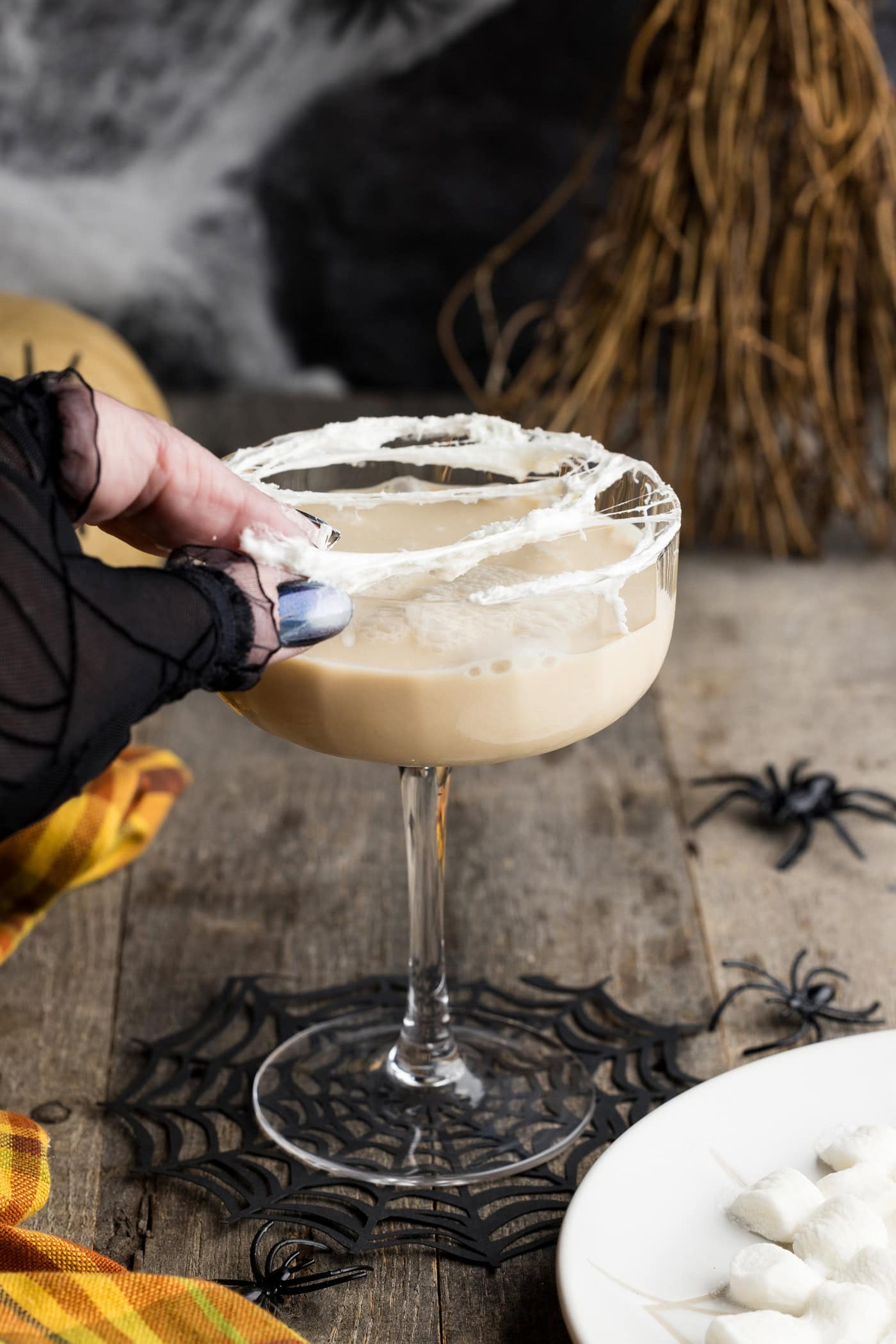hand stretching melted marshmallow over cocktail glass rim