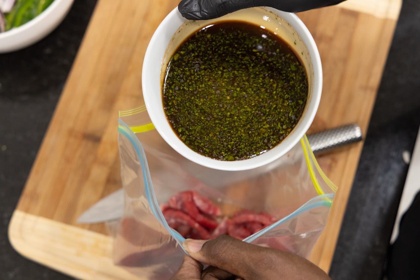 pouring steak marinade into bag with flank steak