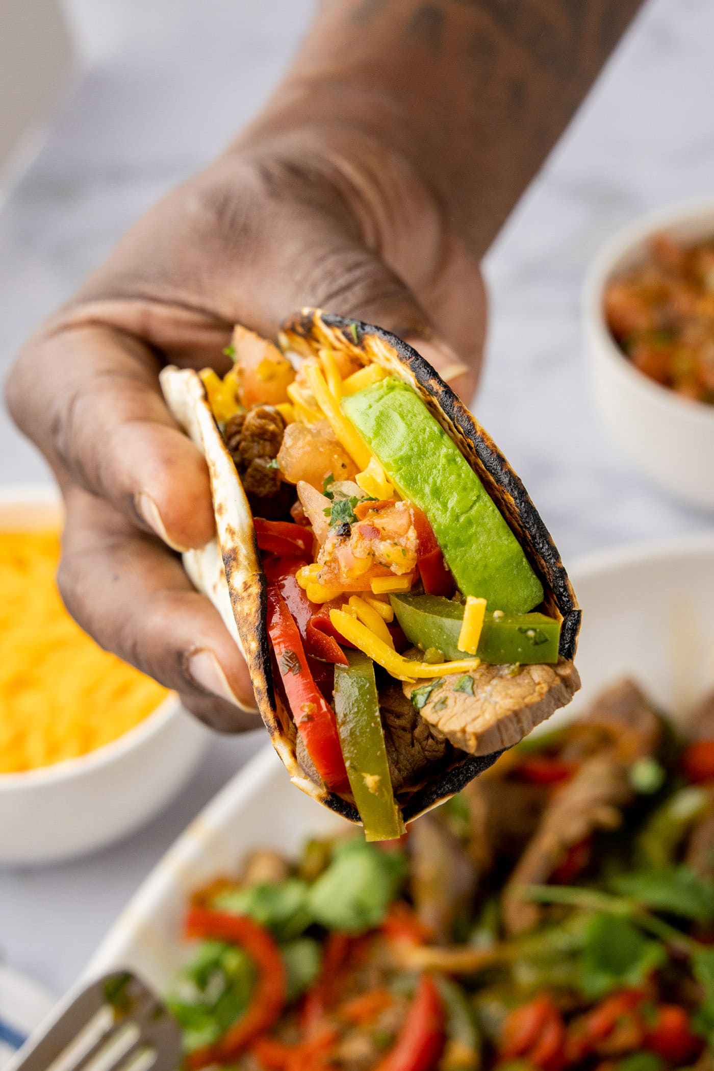 Hand holding Steak Fajitas wrapped in a tortilla