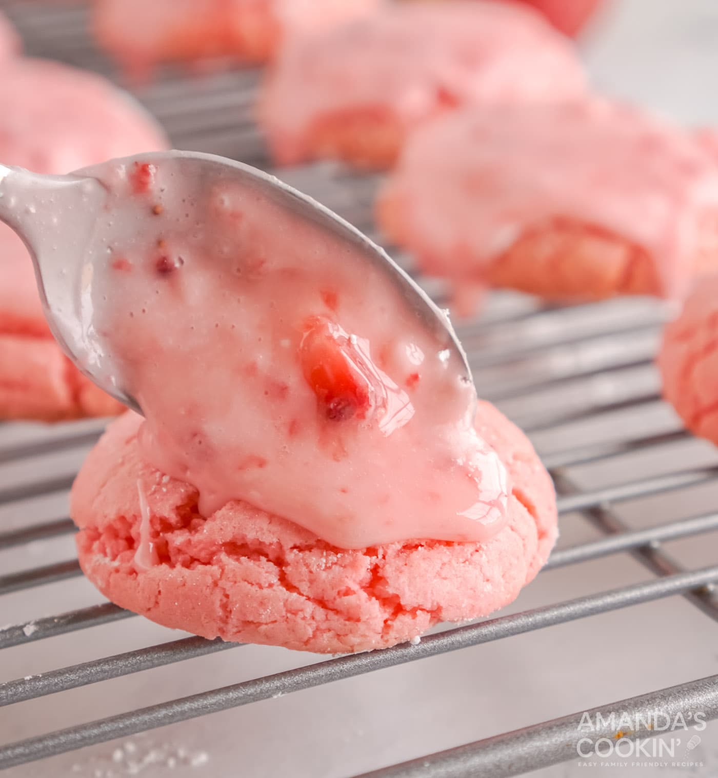 spooning strawberry glaze over cookies