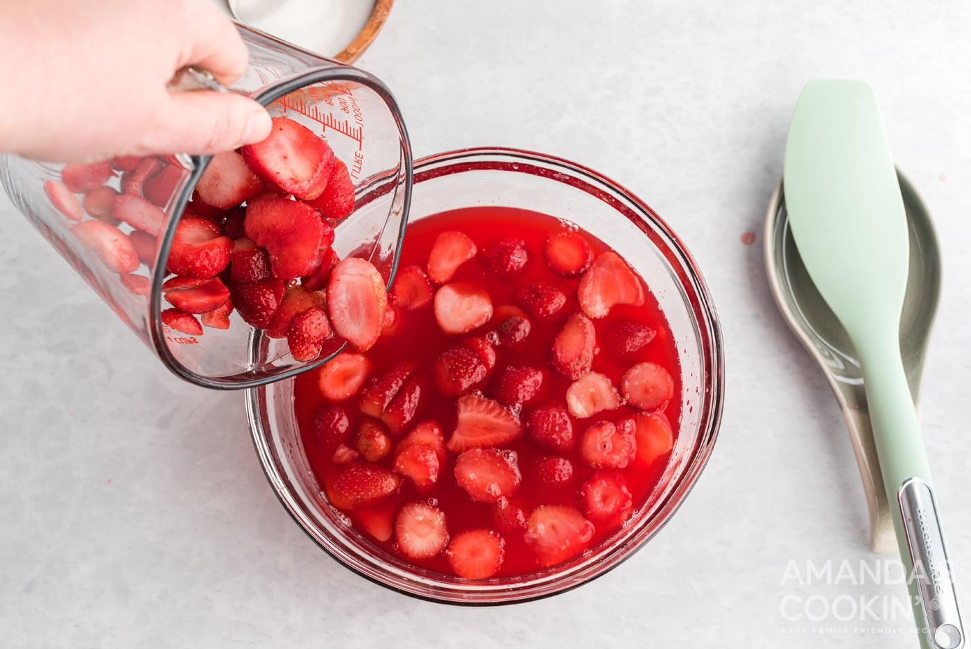 pouring sliced strawberries into a dish with gelatin