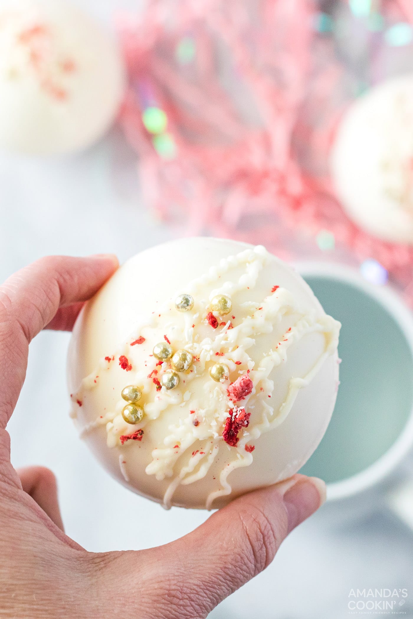 hand holding hot cocoa bomb over a mug