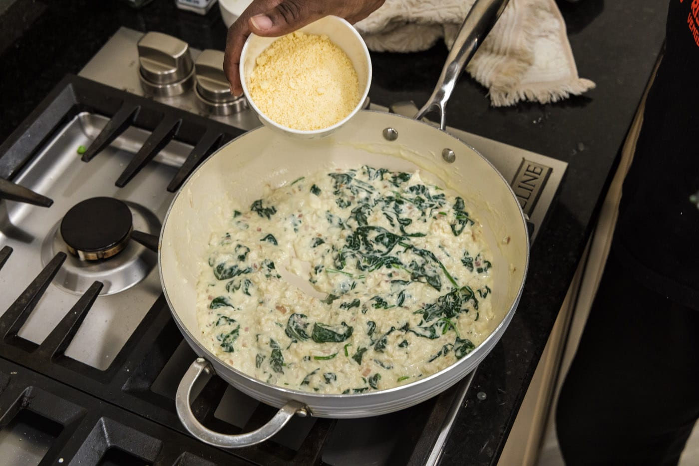 adding parmesan cheese to salmon stuffing in a skillet