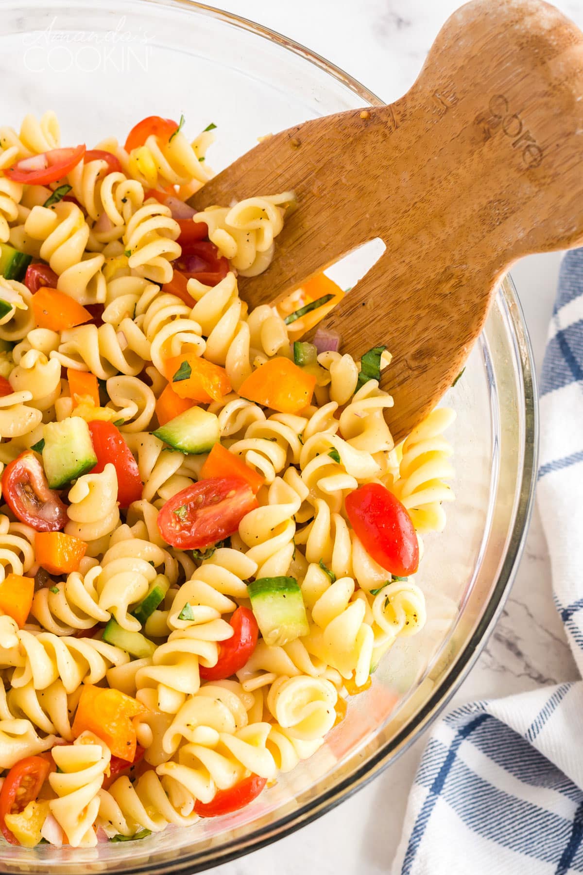 Wooden fork in bowl of summer pasta salad