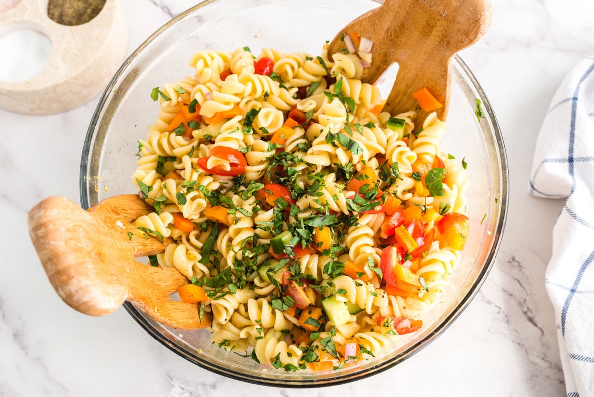 fresh chopped basil sprinkled over pasta salad in a bowl