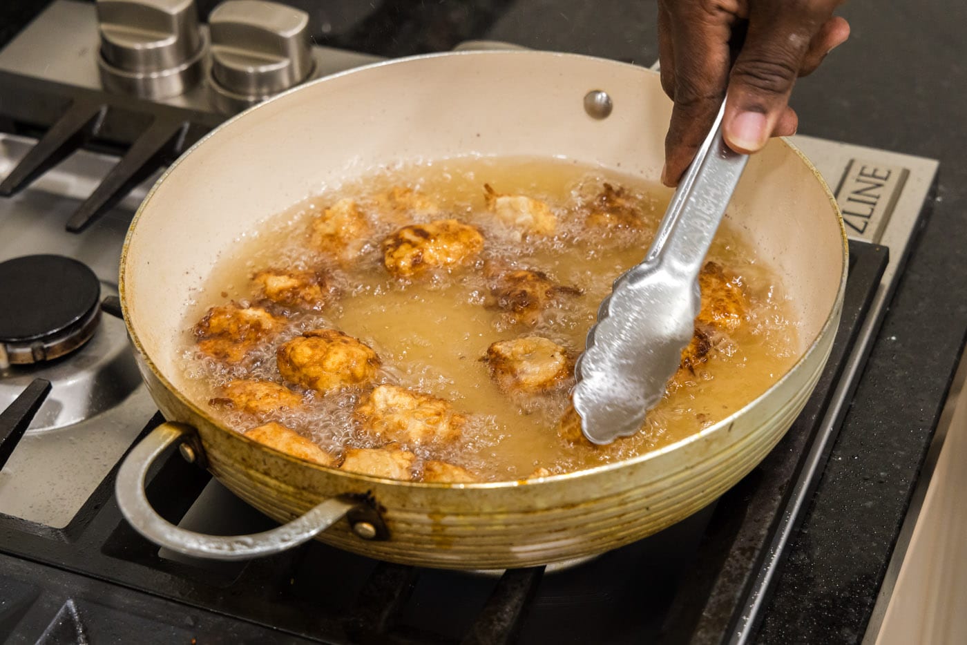 tongs flipping fried pork in oil