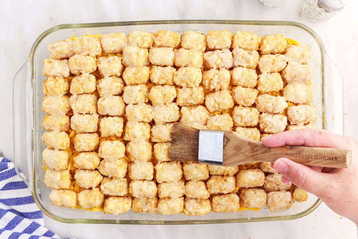 brushing melted butter over tatertots
