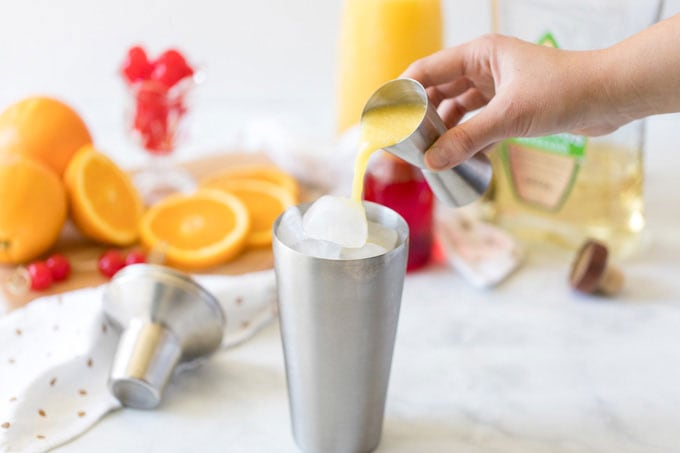 pouring orange juice into cocktail shaker