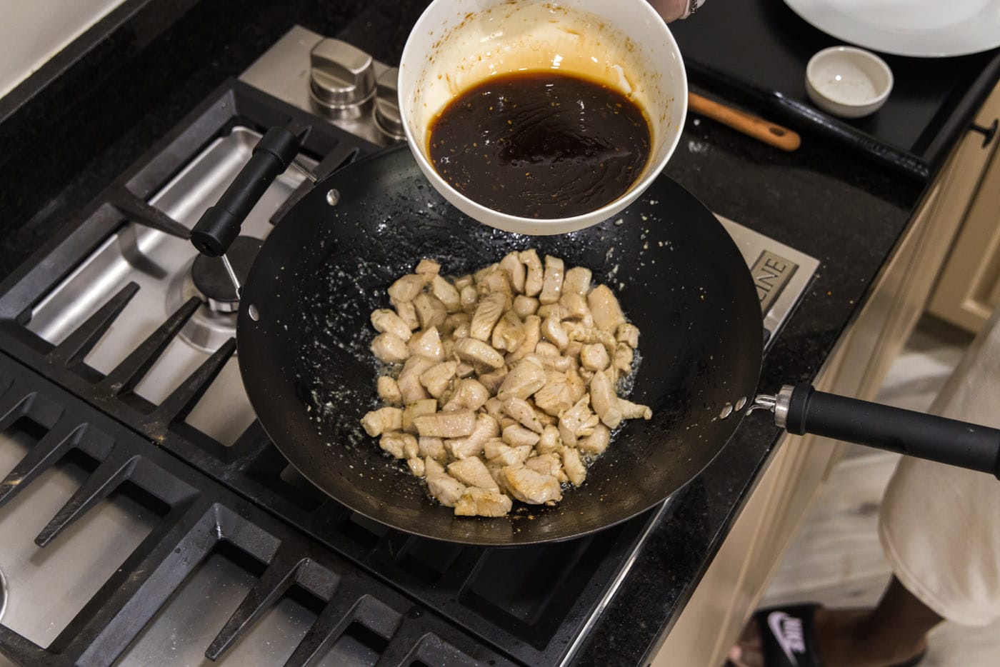 adding teriyaki sauce to wok with chicken