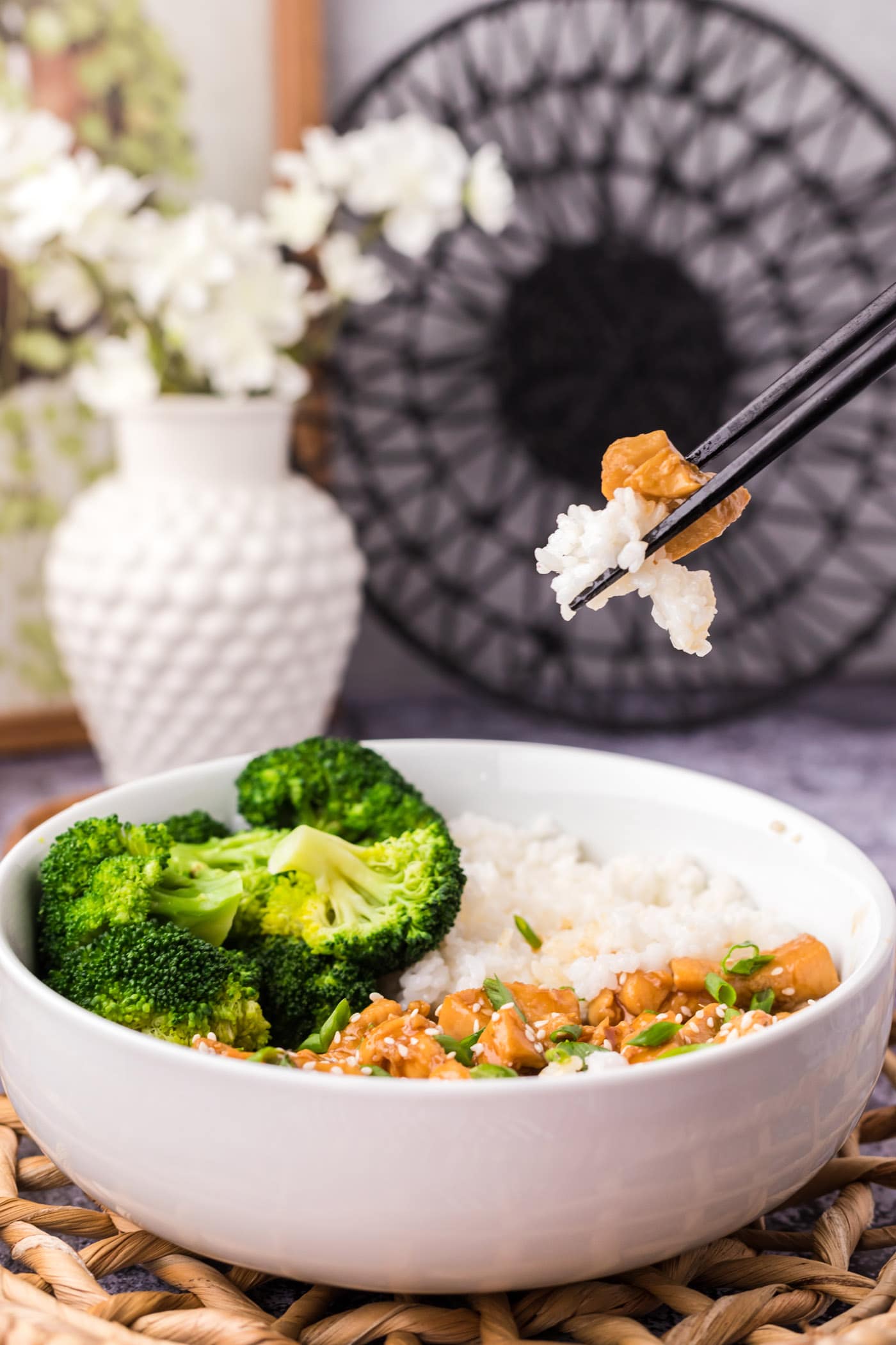 Chopsticks holding a piece of Teriyaki Chicken and rice