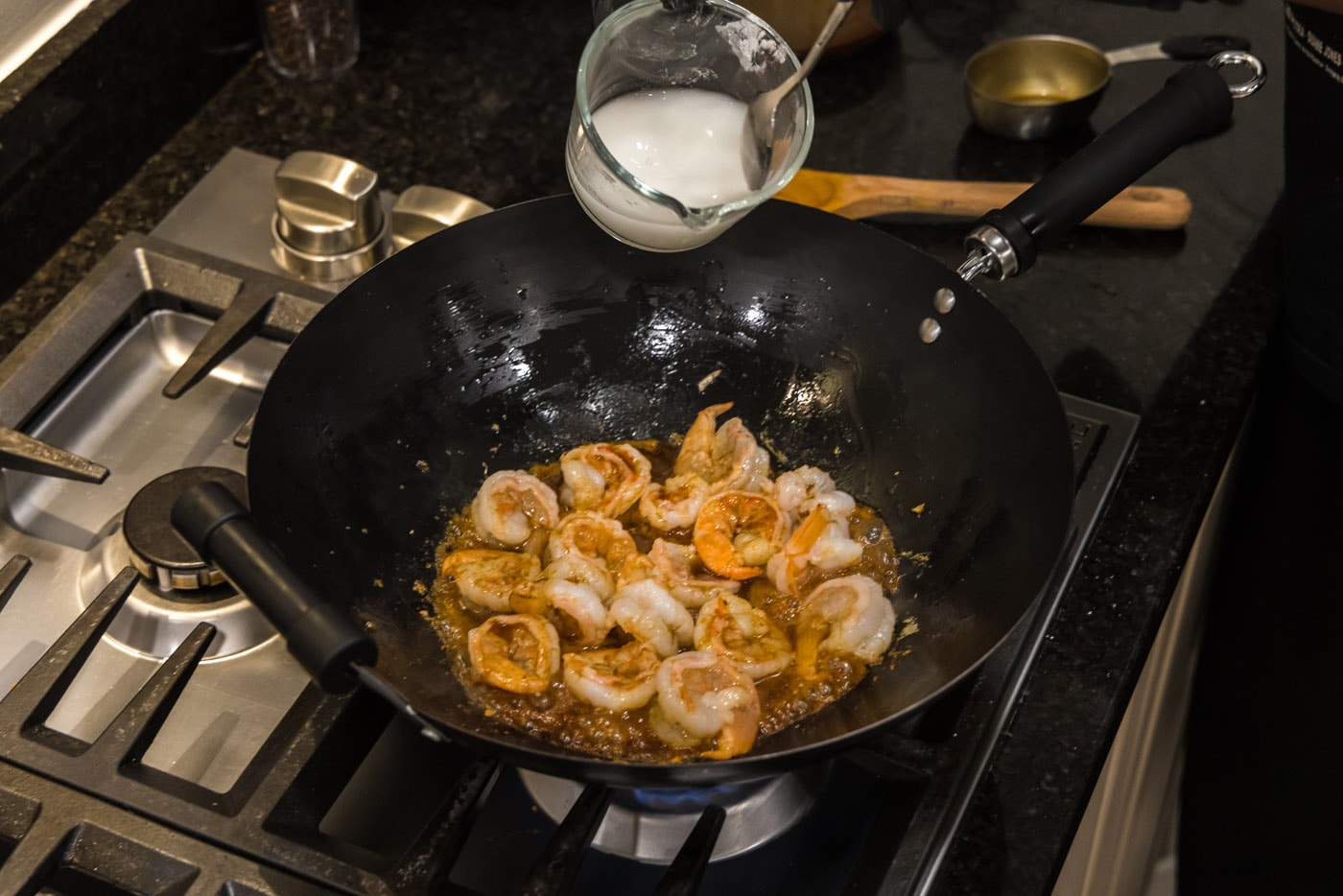 pouring a cornstarch slurry into teriyaki shrimp