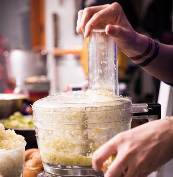A photo of a person using a food processor.