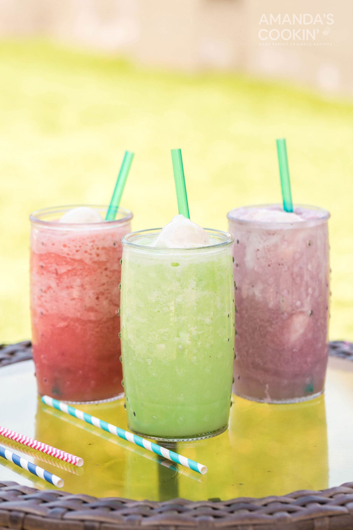 three different colored slushie floats on a table outside