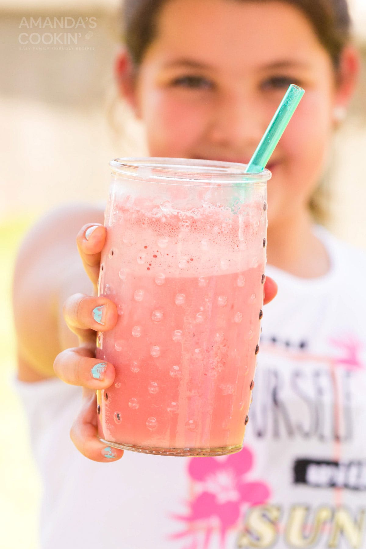 girl holding glass of pink slushie