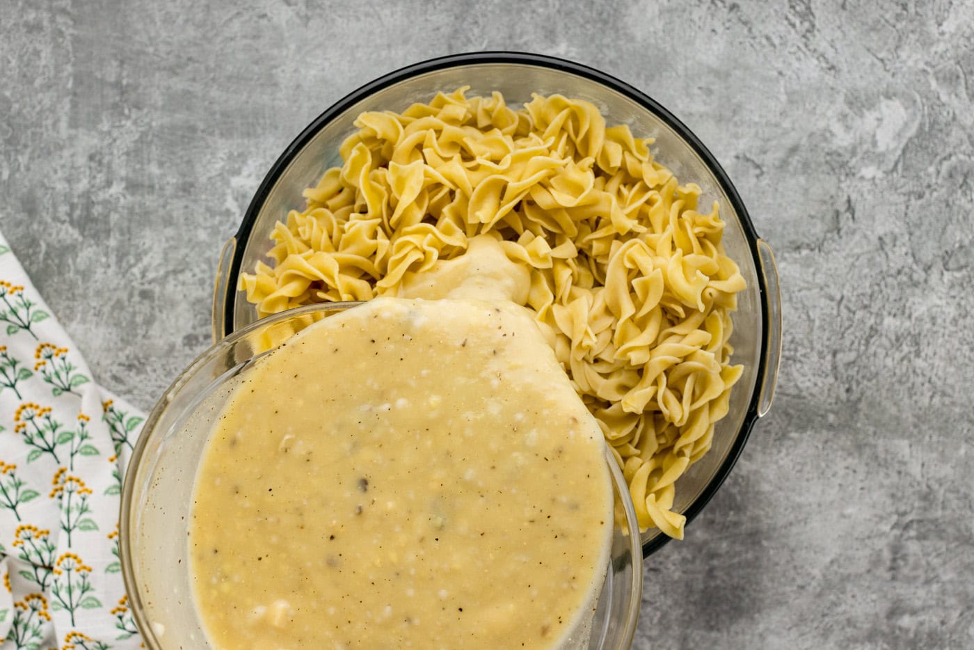 pouring sauce over egg noodles in a bowl