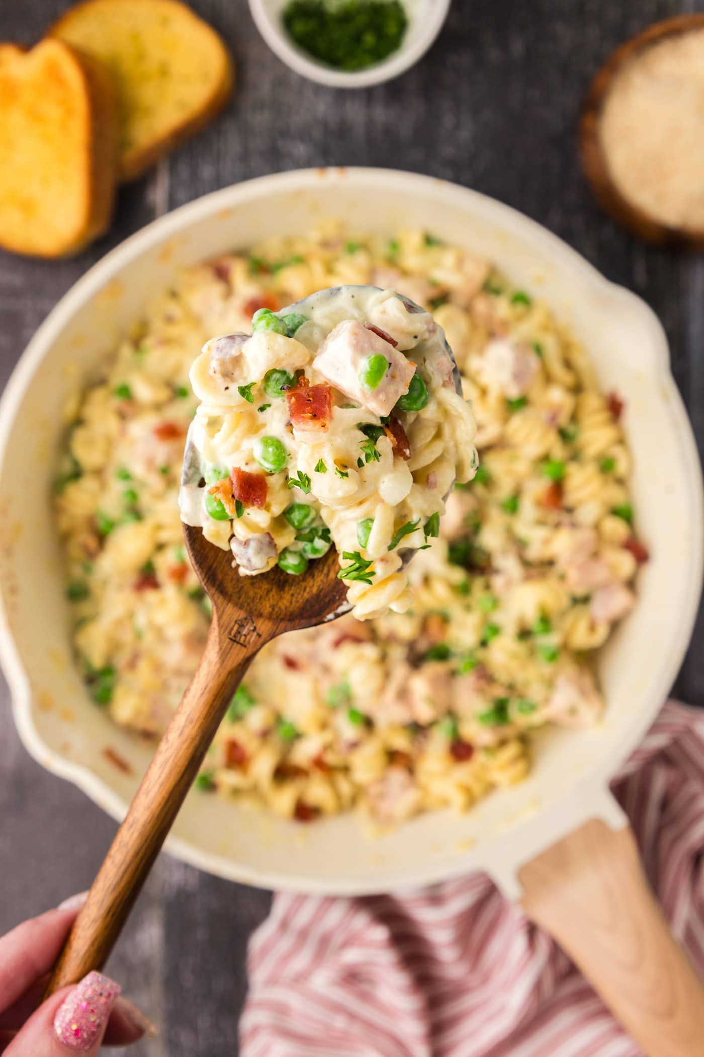 Spoonful of Turkey Carbonara held up above a skillet of Turkey Carbonara