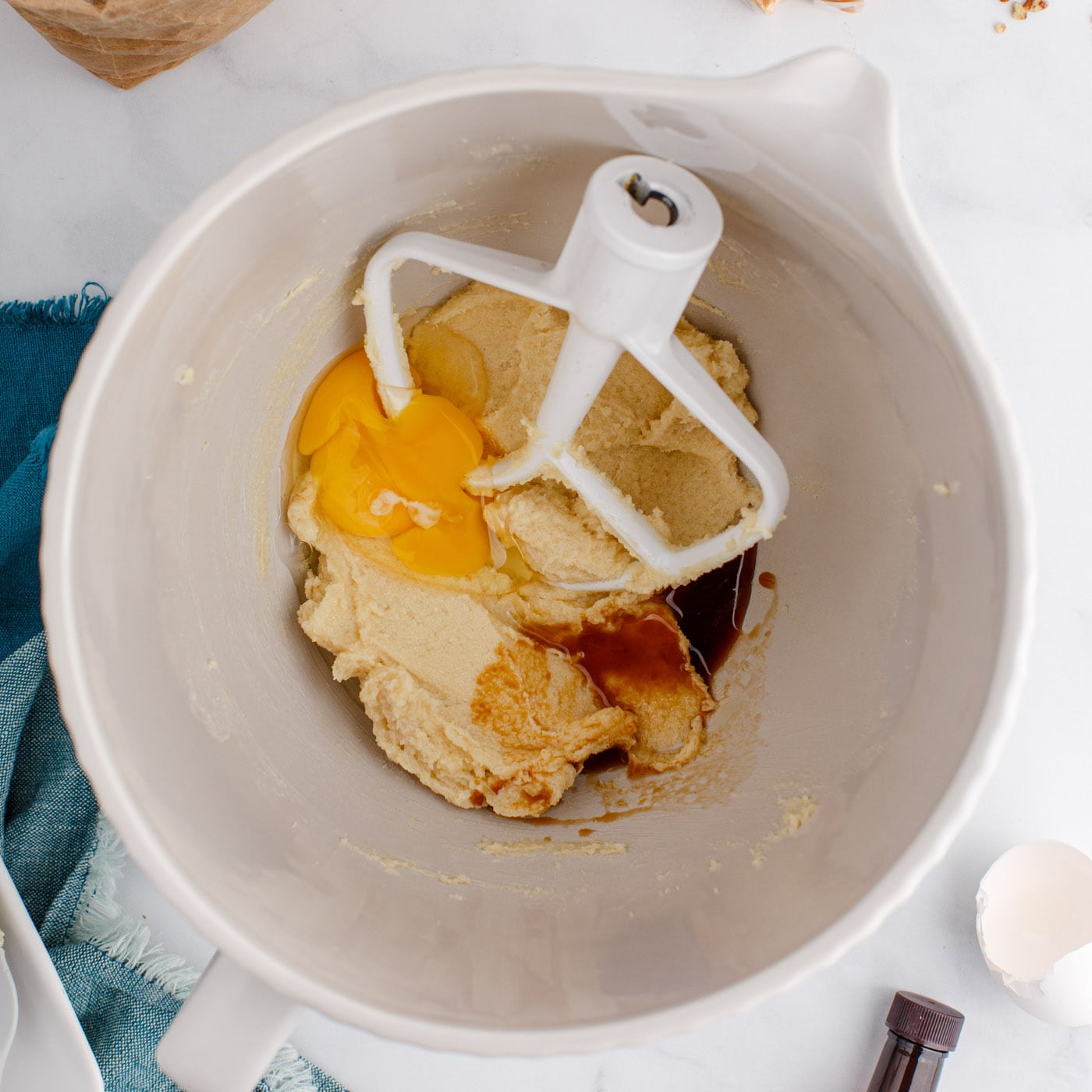 eggs and vanilla added to a mixer bowl with butter and sugars