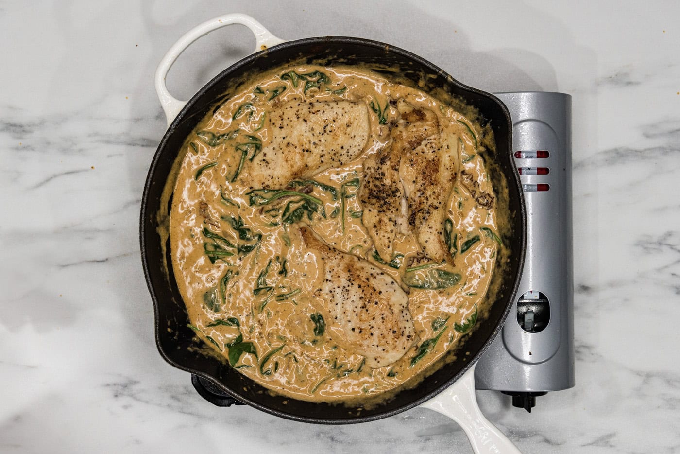 chicken breasts in a skillet with tuscan sauce