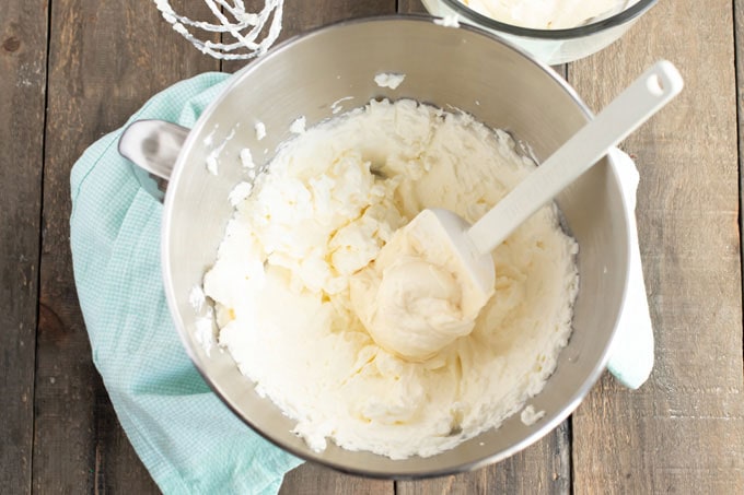 Folding frosting ingredients together in a bowl with a rubber spatula