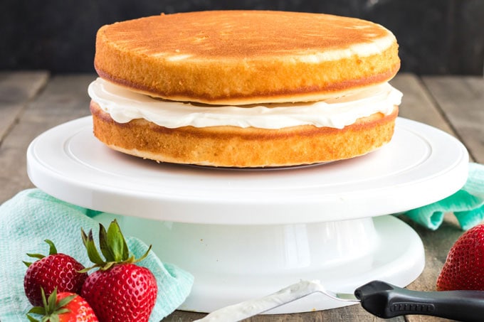 two cake layers with cream cheese frosting in between on a cake platter