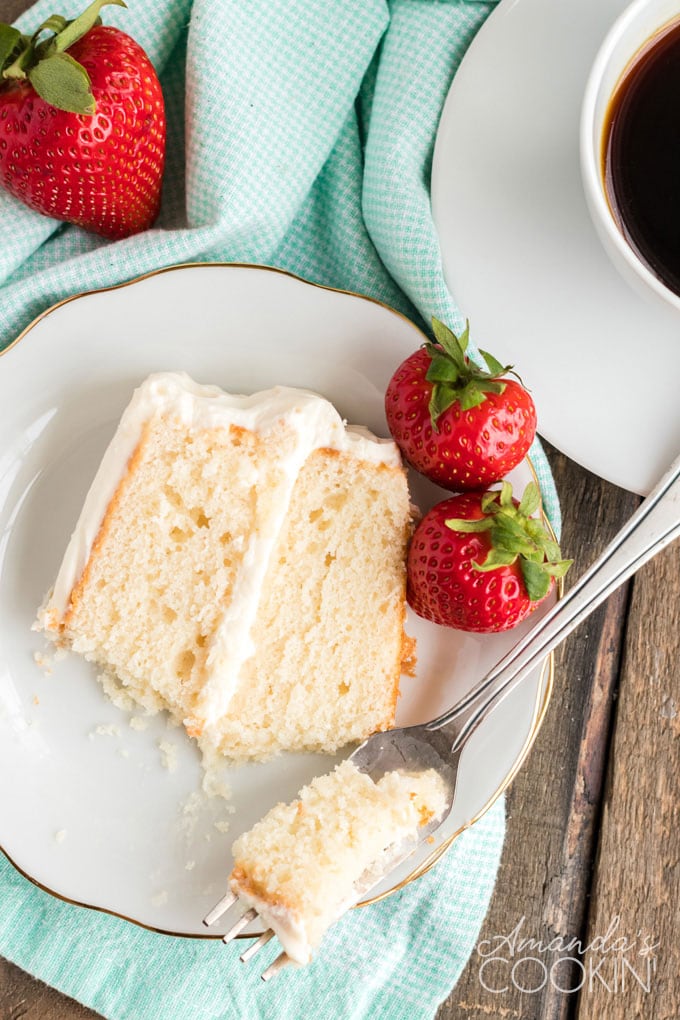 slice of white cake on a plate with strawberries and a fork