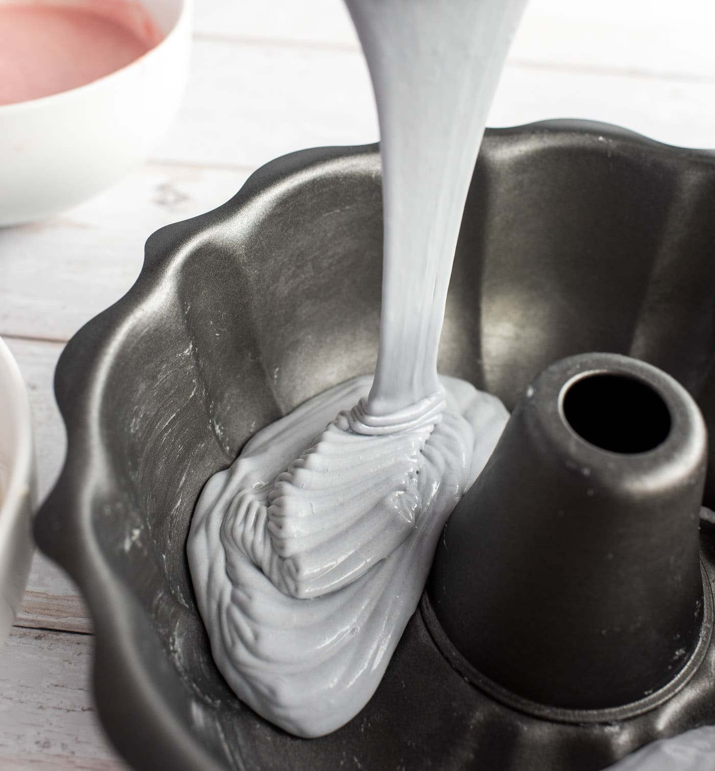 pouring pastel purple cake batter into bundt pan