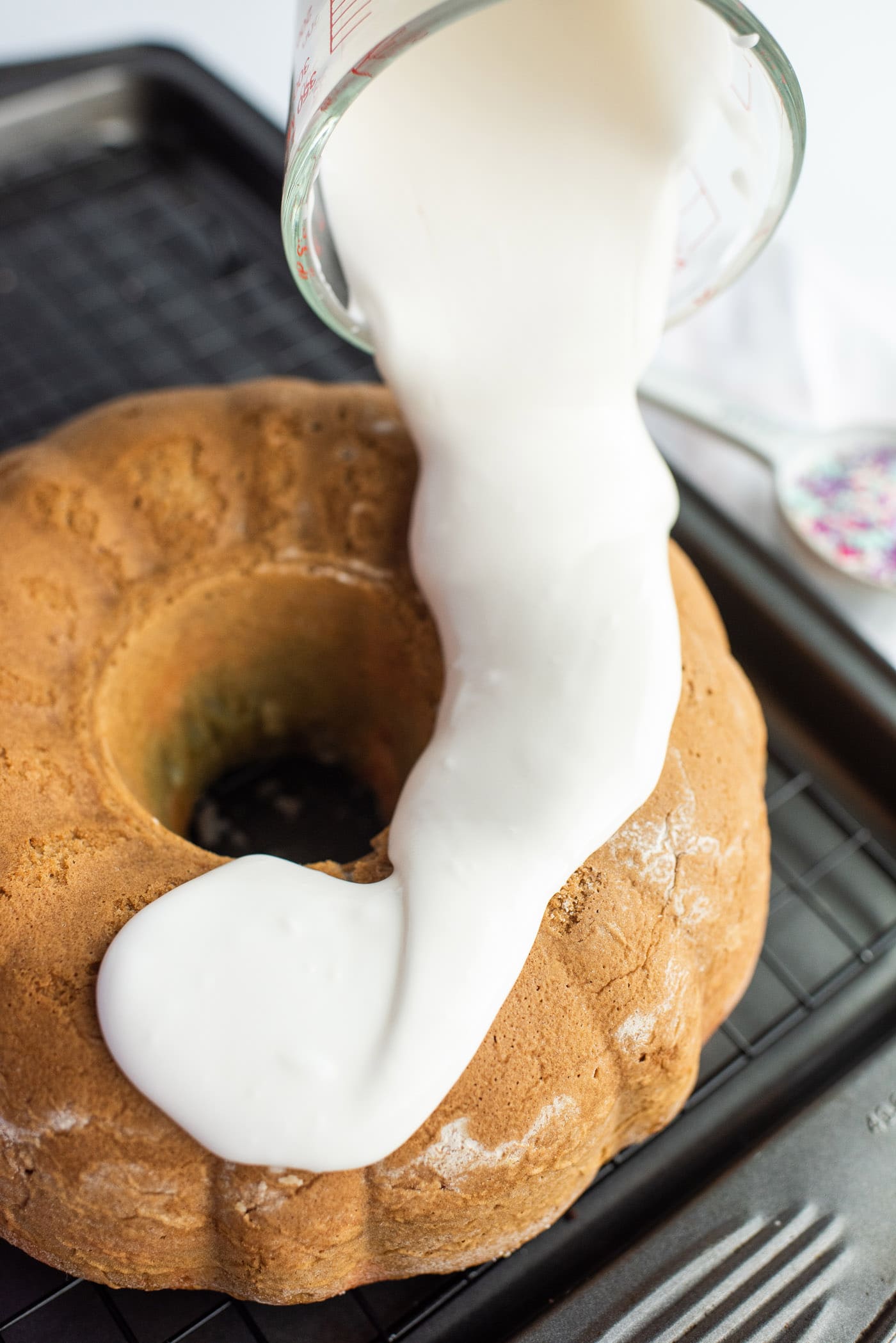 pouring vanilla glaze on bundt cake