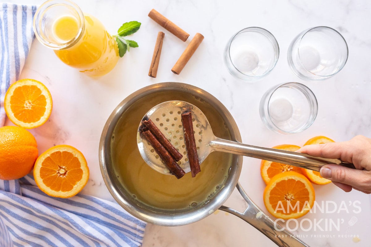 straining cinnamon sticks from saucepan