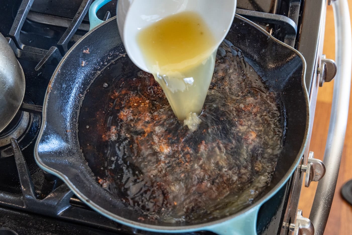 adding chicken broth to skillet