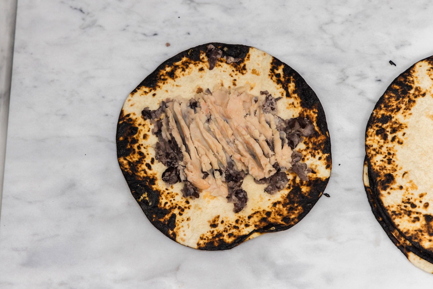 charred tortilla topped with smashed white kidney beans