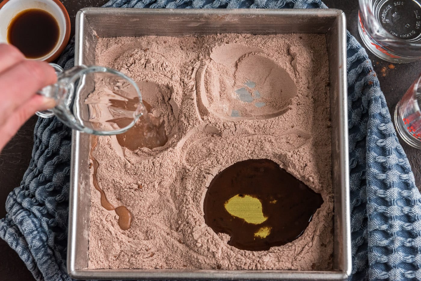 pouring vinegar into well of wacky cake