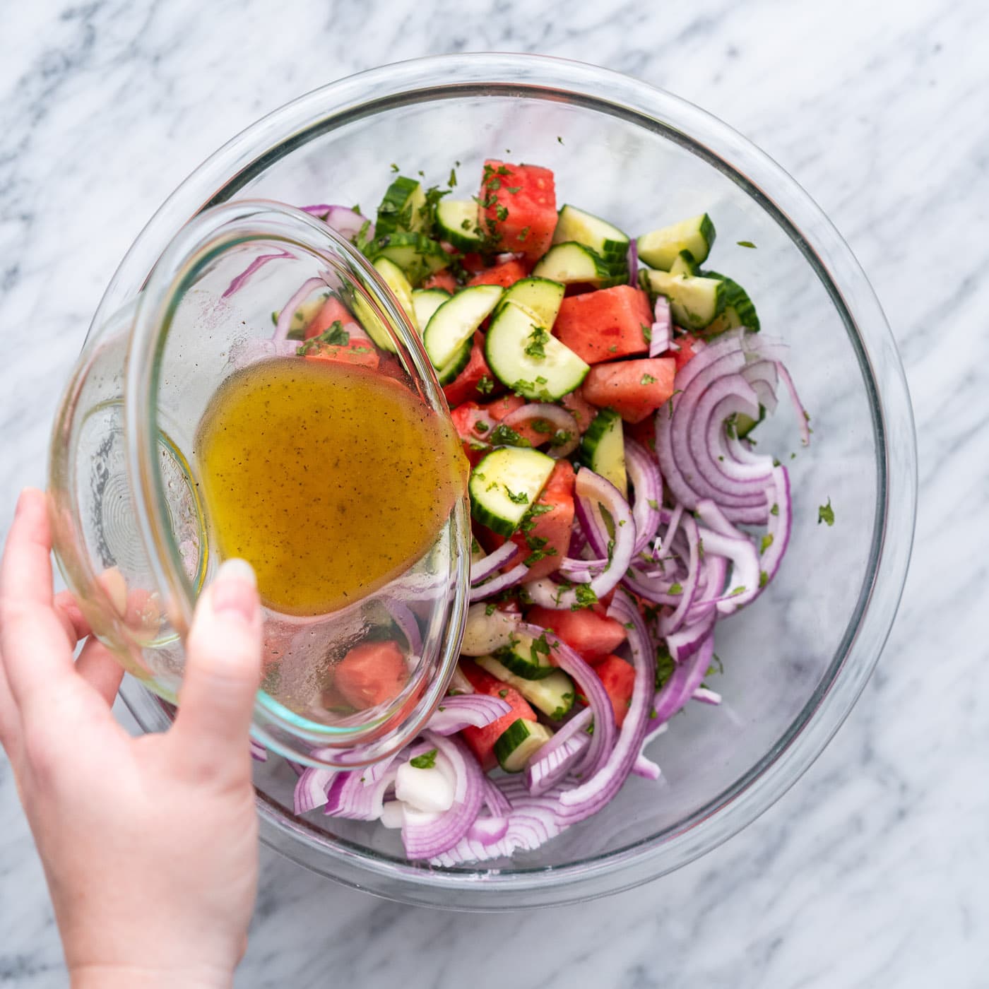 pouring vinaigrette into watermelon salad