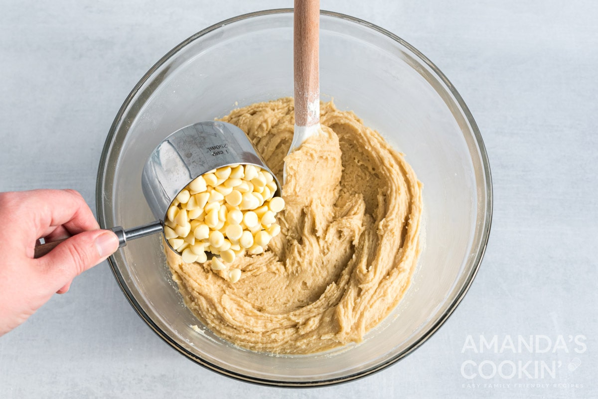 adding white chocolate chips to dough